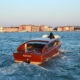 A luxury wooden motorboat cruising past grand Gothic and Baroque palaces on the Grand Canal in Venice, Italy