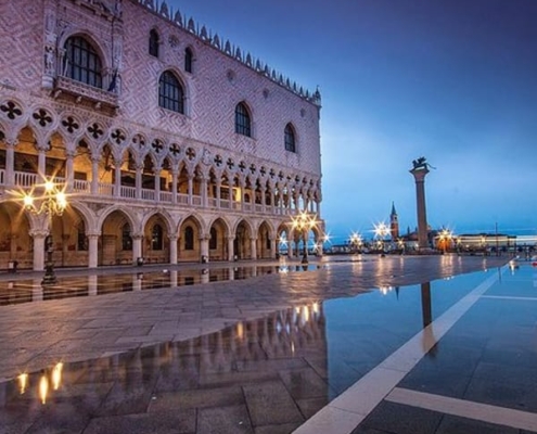 The illuminated Gothic facade of the Doge's Palace and St. Mark's Square at twilight in Venice, Italy